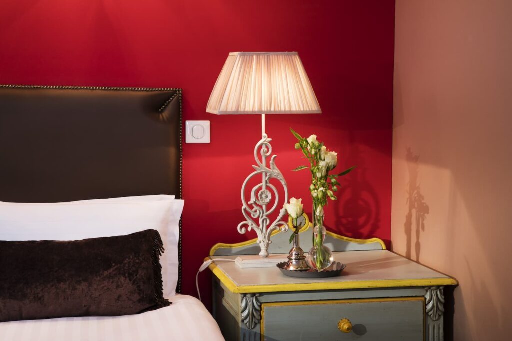 lampe et chevet sur tissus rouge à l'Hôtel des 2 Continents pour un week-end en amoureux à Paris 6