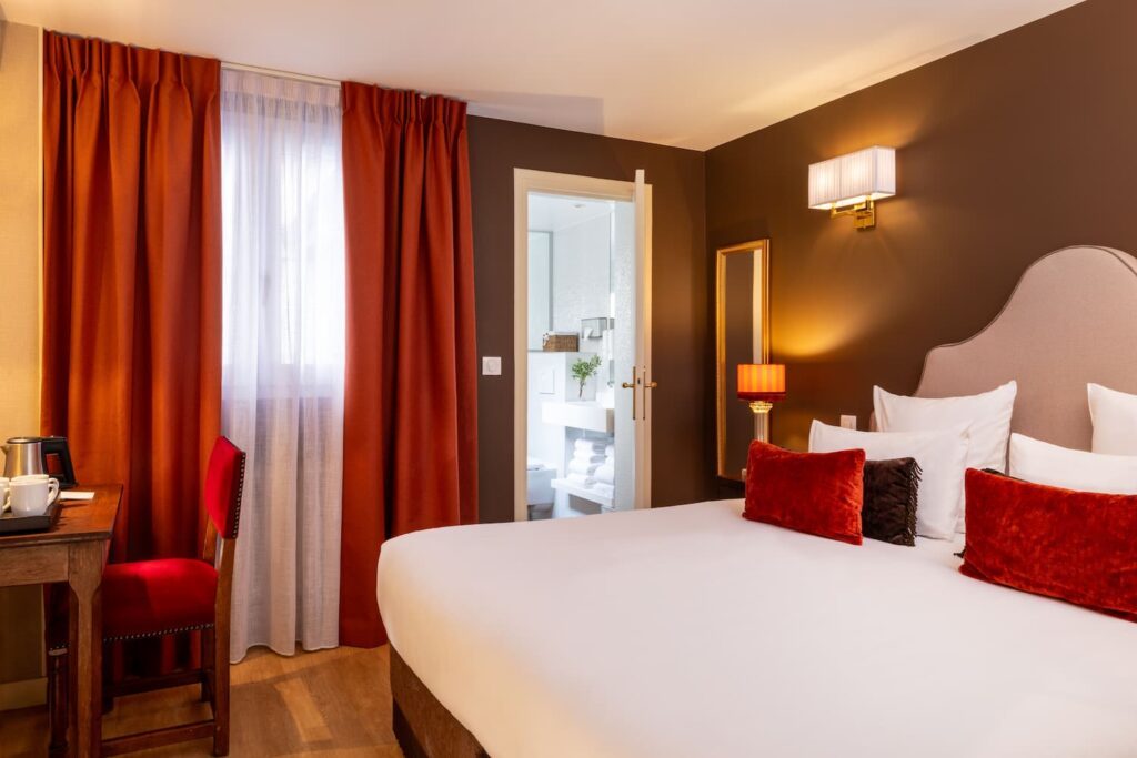 Grand chambre hotel paris - lit king size avec porte ouverte sur une salle de bain | hotel des 2 Continents paris 6