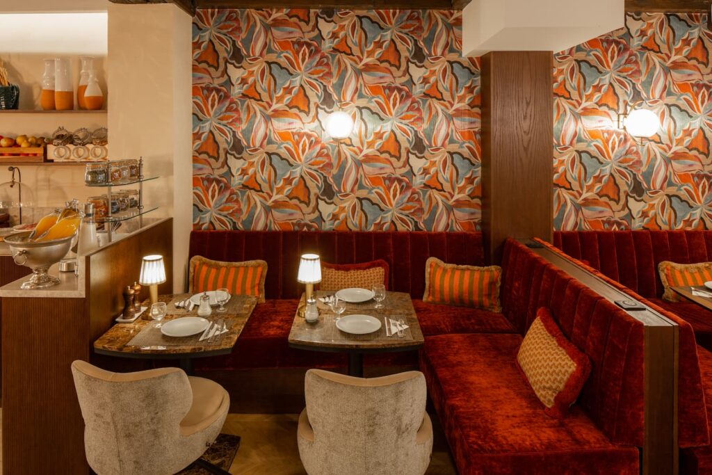 Salle petit-déjeuner avec tables dressées, chaises et papier peint fleuri | hotel 3 étoiles paris 6