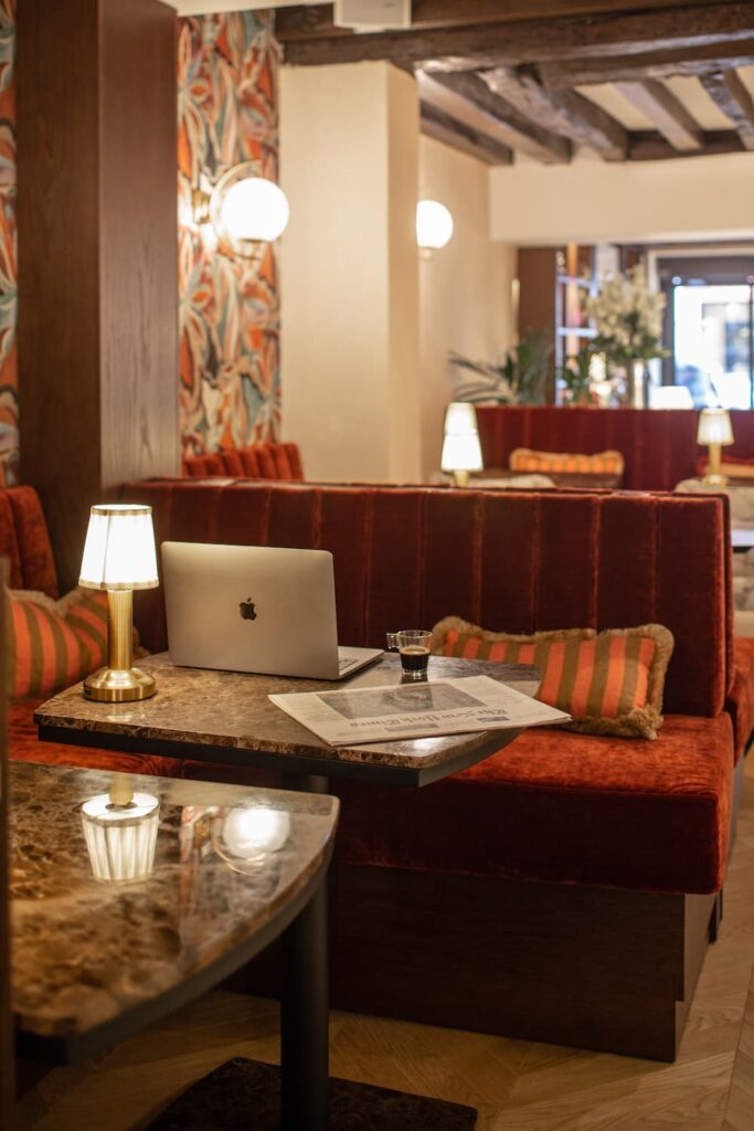 computer on a table with a coffee and a lamp | book a hotel in Paris | hotel des 2 Continents