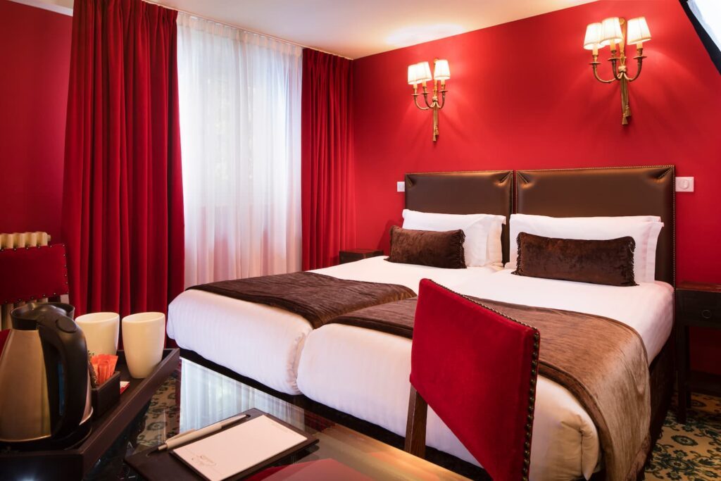 two twin beds, red fabric and curtains, in a hotel connecting room in Paris