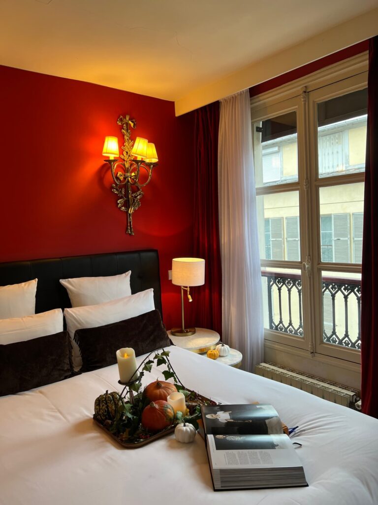 Romantic red room in Hotel des 2 Continents, Paris 6. Halloween decoration and a book on the bed. Perfect for a cosy thanksgiving in Paris. 