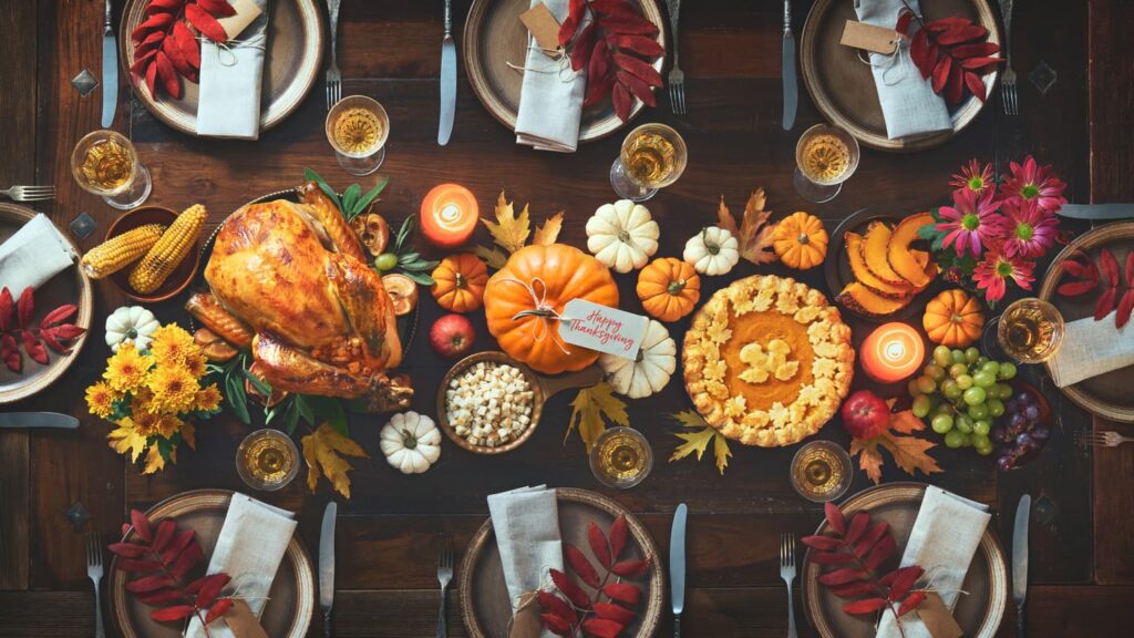 Table with thanksgiving traditional food such as turkey, pumpkin pie, corn. 