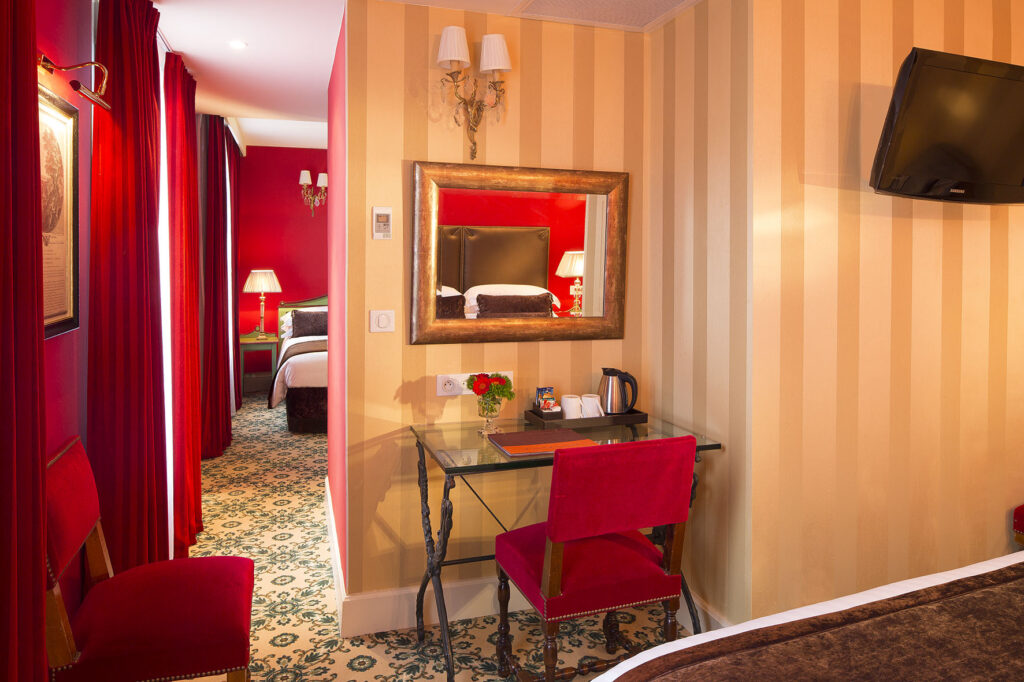 Hôtel Roland Garros Paris: Nous observons une chambre familiale dans les tons rouges (chaises, murs, rideaux) et beige (murs, lampes). Une télévision écran plat est visible à droite de la photo. 