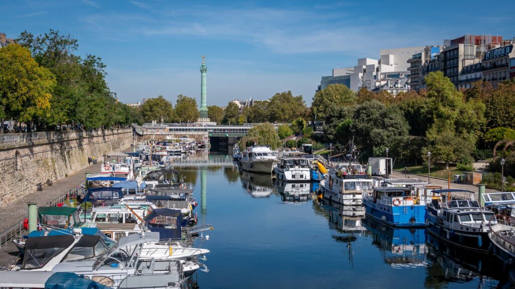 Séjour calme à Paris - Le Port de l'Arsenal. Nous pouvons voir le port avec de nombreux bateaux amarrés. Au loin, nous apercevons la Bastille. 