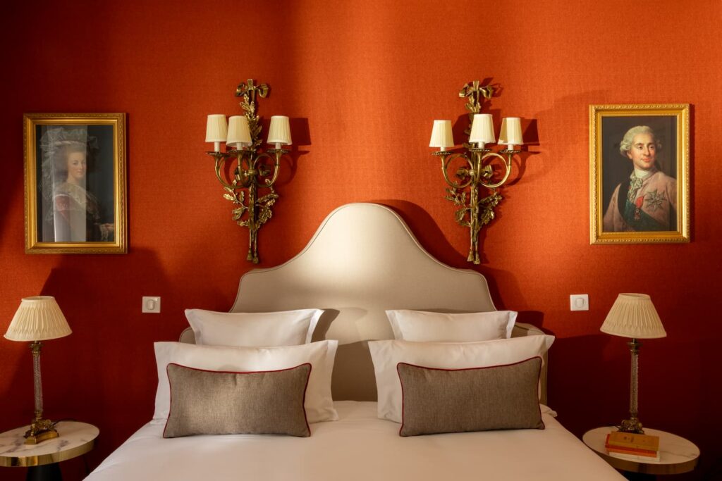 white bed, red fabric, two painted portraits and lights | romantic night in Paris and at the Hotel des 2 Continents